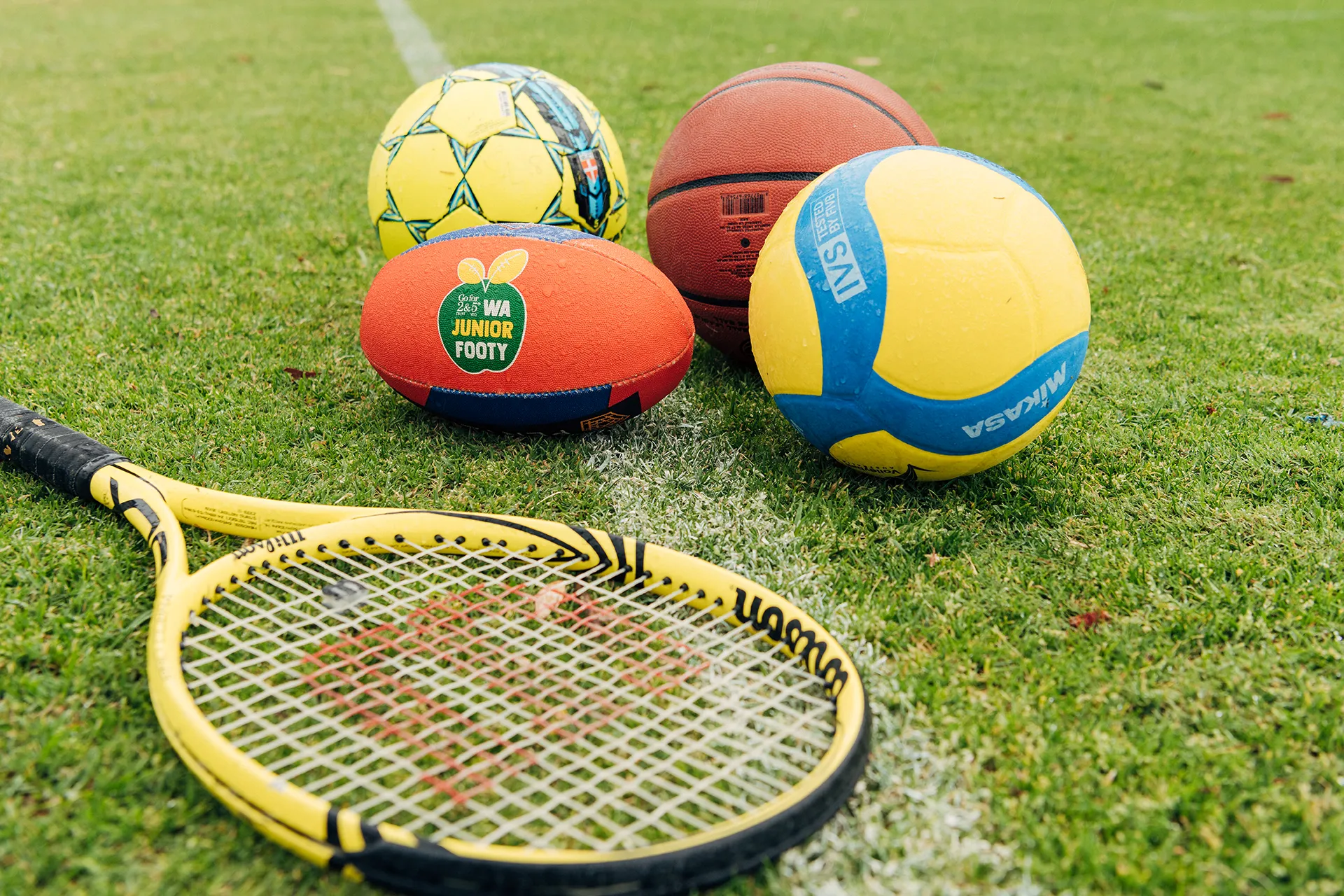 Closeup of racquet and balls laying on grass